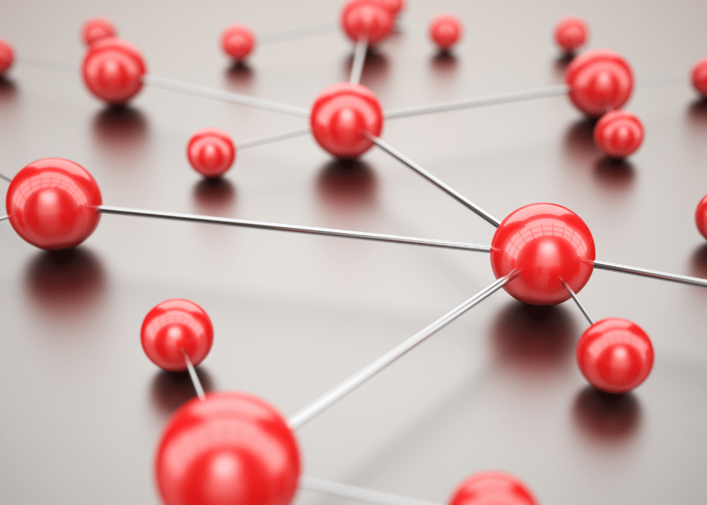 Rote Kugeln, verbunden durch dünne Drähte, bilden ein Netzwerk auf einer glatten Oberfläche.