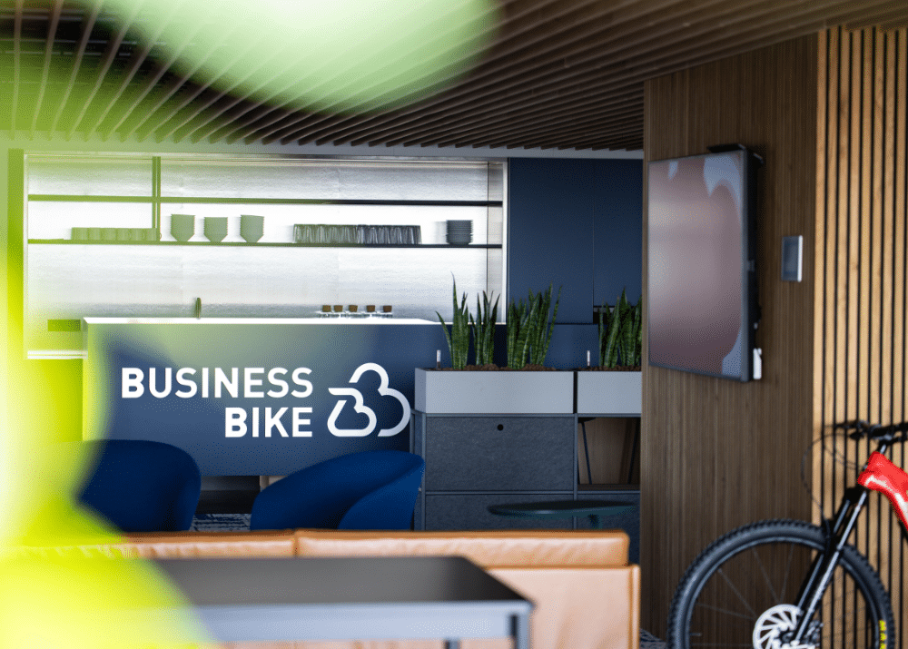 Moderne Büroumgebung mit Pflanzen, einem Empfangstresen mit "BUSINESS BIKE"-Logo und einem Fernseher.