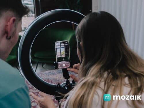 Zwei Personen nutzen einen Ringlicht-Ständer, um mit einem Smartphone ein Bild aufzunehmen.