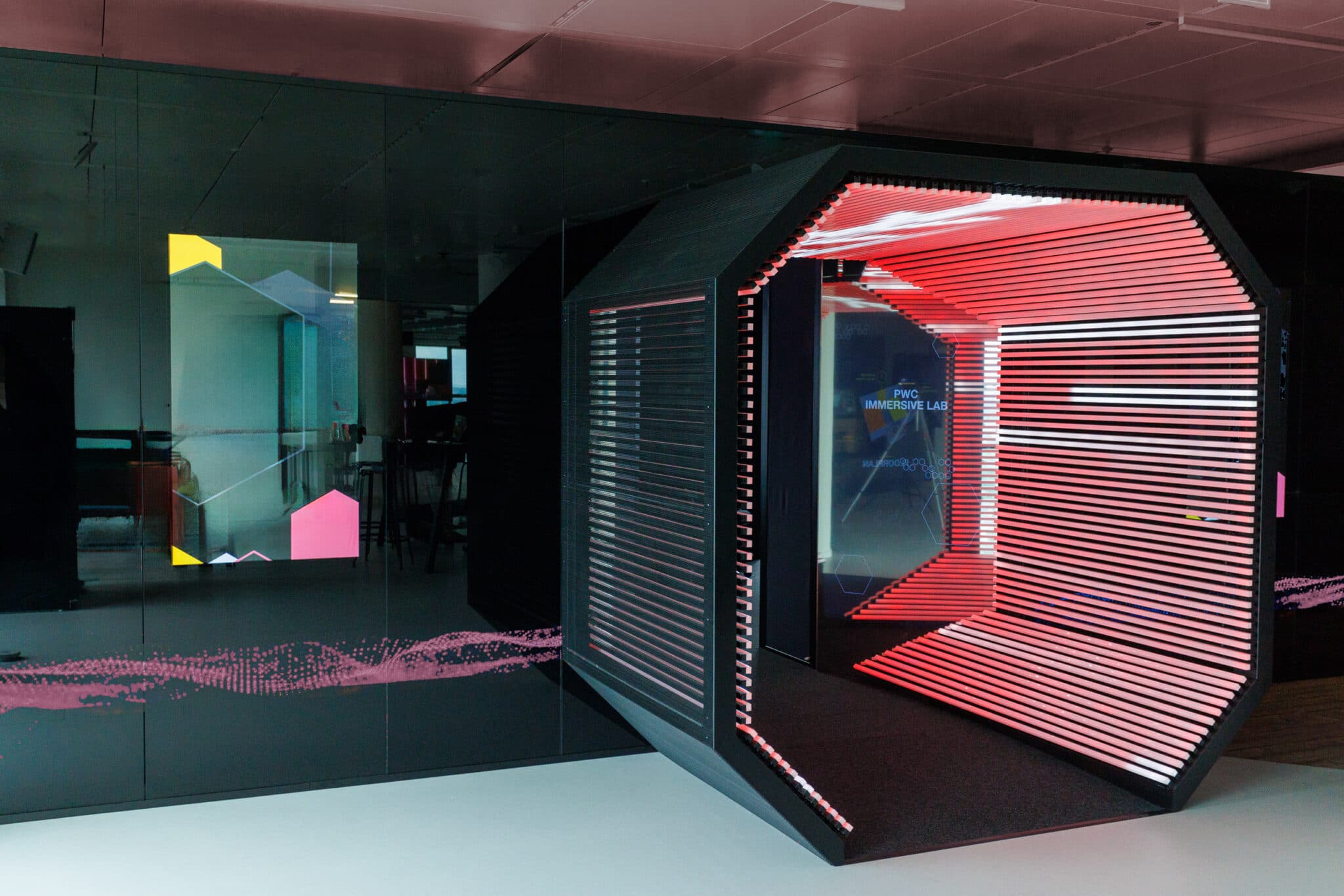 Futuristischer Raum mit einem hexagonalen Eingang, beleuchtet in Rot und Pink, umgeben von modernen, grafischen Elementen.