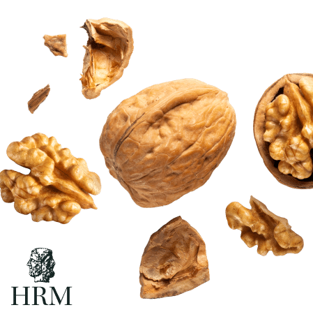 hrm_nut Eine ganze Walnuss und ihre Stücke auf hellem Hintergrund, umgeben von Walnusskernen. HRM-Logo unten links.