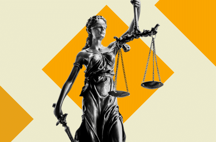 Skulptur der Justitia mit Waage und Schwert vor orangefarbenen geometrischen Formen.