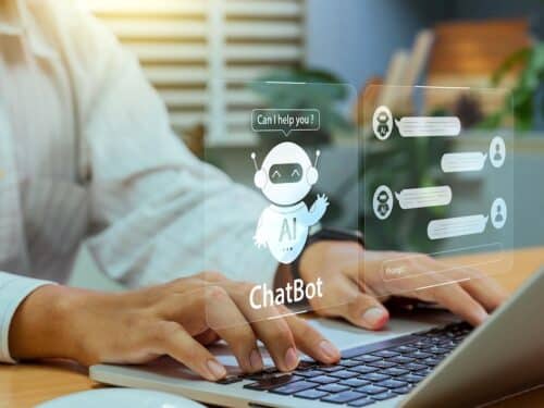 Person tippt auf Laptop, während ein virtueller KI-Chatbot mit Sprechblase auf dem Bildschirm angezeigt wird.