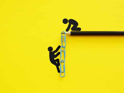 Papierclip-Kettenleiter auf gelbem Hintergrund, mit Figuren, die Unterstützung und Teamarbeit symbolisieren.