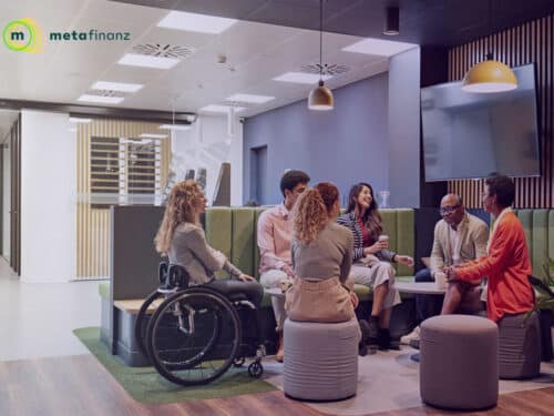 Gruppe von sechs Personen in einem modernen Büro, die in einem Gespräch auf Sitzmöbeln sitzen.
